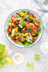 Salted salmon salad with fresh green lettuce, cucumbers, tomato, bell pepper and red onion. Ketogenic, keto or paleo diet lunch bowl. Top view