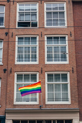 Gay flag in Amsterdam. Gay rainbow flag on a building. Rainbow flag of the LGBT community on the building on street Amsterdam. 
