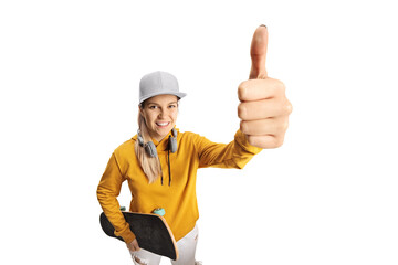 Female teenager with headphones and a skateboard showing a thumb up sign in front of camera