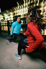 The night runners doing warm-up exercises at the urban exterior. Night runners stretching legs.