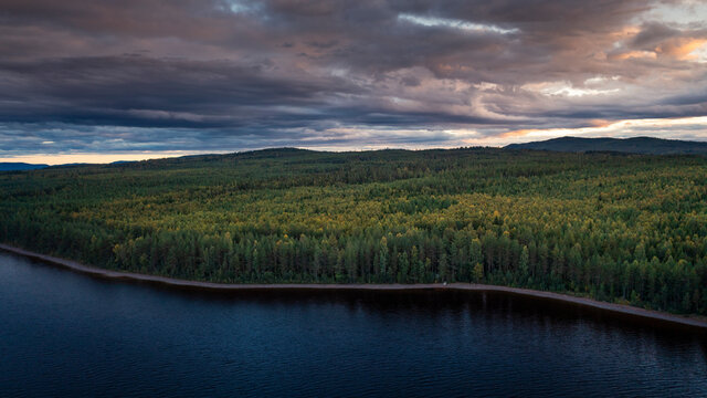 Green forest and lakeshore at Lake Siljan from above during sunset in Dalarna, Sweden.