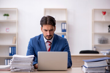 Obraz premium Young male employee and too much work in the office