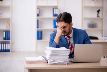 Naklejka premium Young male employee and too much work in the office