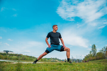 Naklejka na ściany i meble Man stretching hamstring arms muscles during outdoor crossfit workout