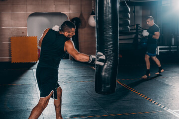 Fit professionalkick  boxing man kicking at punching bag