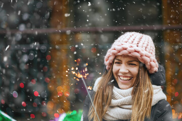 Lovely lady playing with sparklers during the snowfall