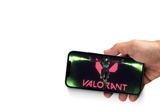 Male hand holding a smartphone with Valorant mobile game app on the smartphone screen on white background. Rio de Janeiro, RJ, Brazil. December 2021