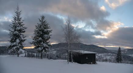 Panorama of Black modern tiny cabin on snowy Carpathian mountains in Ukraine