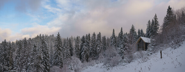 Panoramic shot of Modern barn house hidden in snowy pine trees forest