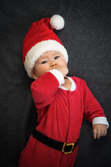 cute newborn baby in christmas outfit with santa claus hat lying on grey background for xmas