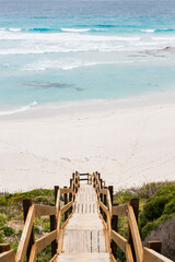 Relaxing summer-day beach background following the wooden path, in Western Australia. Calmness and motivational background design.