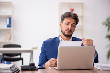 Young male employee unhappy with excessive work in the office