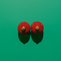 Christmas season surreal concept, red baubles against dark green background. Minimal creative idea with New Year and winter decoration. Visual abstract composition.
