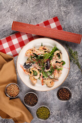 seafood salad. on a white plate on a gray table background. near spices and fabric