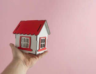 Fototapeta na wymiar A toy house on the palm with a pink background. House, home, real estate creative minimal concept with copy space. 