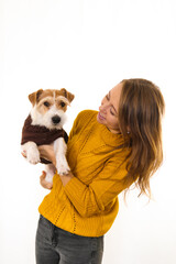 Naklejka na ściany i meble Laughing Girl in a yellow jacket is holding a dog in her arms. Isolate on white background