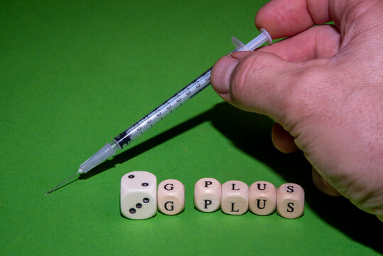 Concept Image 2G plus and 3G plus, letter cubes form 2G and 3G plus against a green background, male hand with a syringe