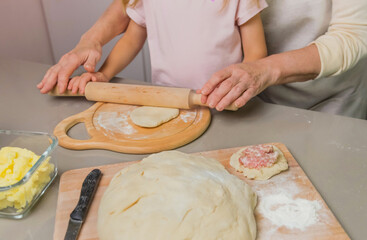 grandmother and granddaughter roll out cake dough