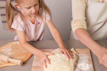 little girl prepares dough with her grandmother