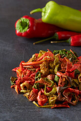 Assortment of Dried and Fresh Yellow, Green, Red and Orange Peppers on a Dark Grey Background.
