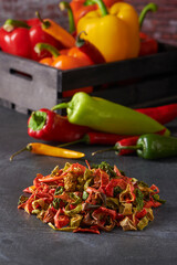 Assortment of Dried and Fresh Yellow, Green, Red and Orange Peppers on a Dark Grey Background.