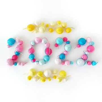 New Year 2022. Blue, pink and yellow balls of knitted yarn