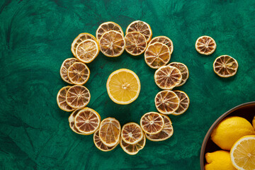 Dried Lemons on a Circle on a Green Background with Fresh Lemons in a Wooden Bowl. Dried Fruit Concept