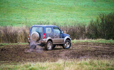 4x4 off-road vehicle driving across mud and water-logged terrain, Wilts UK. Suzuki Jimny