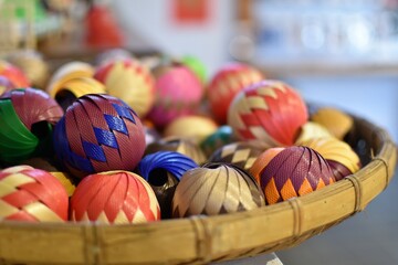 Decorative rattan wicker balls with colorful patterns on a woven winnowing tray basket