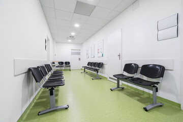 Fototapeta na wymiar Chairs lined up in a hospital waiting room. Hospital interior with green floor without people.