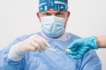 Surgery and Medical theme: close up of male doctor holding syringe with injection and anesthesia solution.