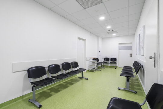 Chairs lined up in a hospital waiting room. Hospital interior with green floor without people.