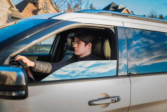 Teenage boy sitting in driver's seat of vehicle learning to drive.