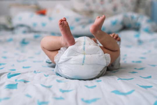View of a baby lying in bed. Feet up and diaper.