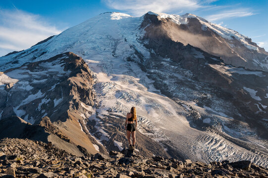 Fit female standing on a cliff next to Mount Rainier