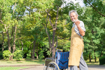 車椅子を押すシニア男性　介護福祉士