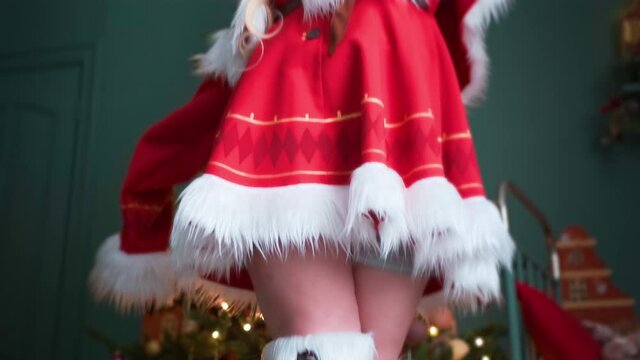 Cute little girl in a red costume of the New Year's elf. Posing for the photographer. New Year theme