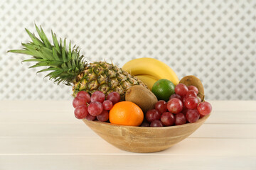 Fresh ripe fruits in bowl on white wooden table
