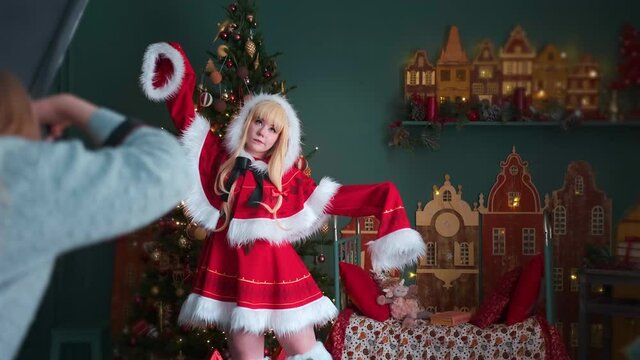 Cute little girl in a red costume of the New Year's elf. Posing for the photographer. New Year theme