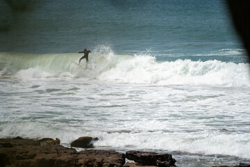 male surfer catching waves surfing at south coast beach on a bright warm sunny day on clear blue...