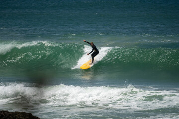 male surfer catching waves surfing at south coast beach on a bright warm sunny day on clear blue water