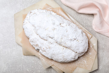 Fototapeta na wymiar Delicious Stollen sprinkled with powdered sugar on light table, top view