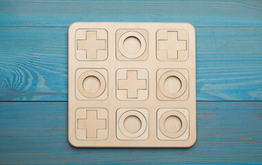 Tic tac toe set on light blue wooden table, top view