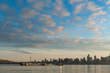 Naklejka premium Seattle Skyline at Dawn. Sunrise on Elliott Bay when marine traffic is active with ferries and tugboats crisscrossing the water with the beautiful city skyline in the background.