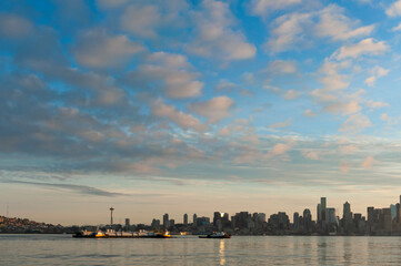 Seattle Skyline at Dawn. Sunrise on Elliott Bay when marine traffic is active with ferries and tugboats crisscrossing the water with the beautiful city skyline in the background.