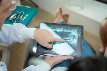 Dentist and patient commenting treatments in a tablet application in a consultation,Dentist and patient in dentist office.