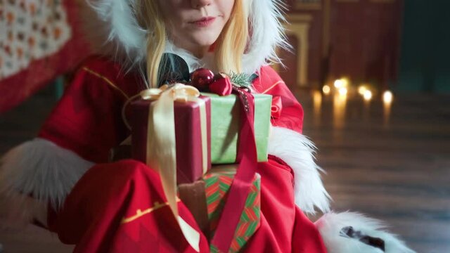 Cute girl cosplaying Christmas Miku Santa dress with gifts. New Year's elf. Sits on the floor