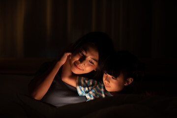 Obraz na płótnie Canvas young Asian mother and little daughter girl on bed, cozy love sleepy at childhood home, at night