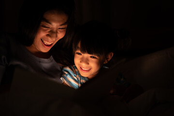 young Asian mother and little daughter girl on bed, cozy love sleepy at childhood home, at night