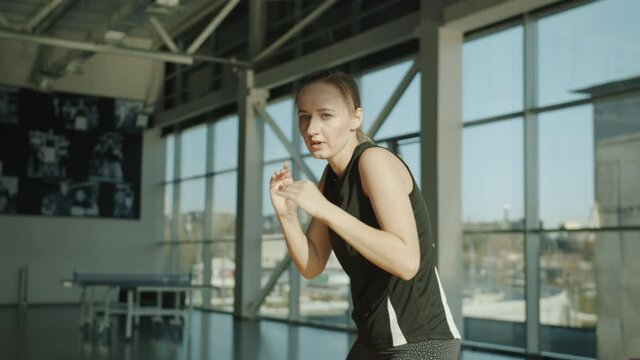 Portrait of young lady in sportswear practicing kickboxing movements in modern gym. Active lifestyle and leisure time activities concept.